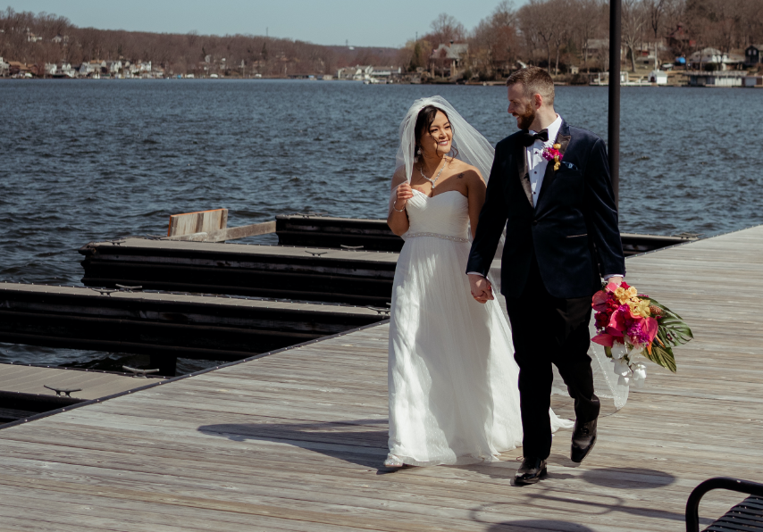 Bride and groom walking down a dock holding hands