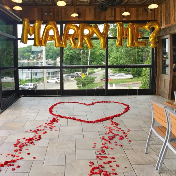 Marry me sign in private room with roses in the shape of a heart